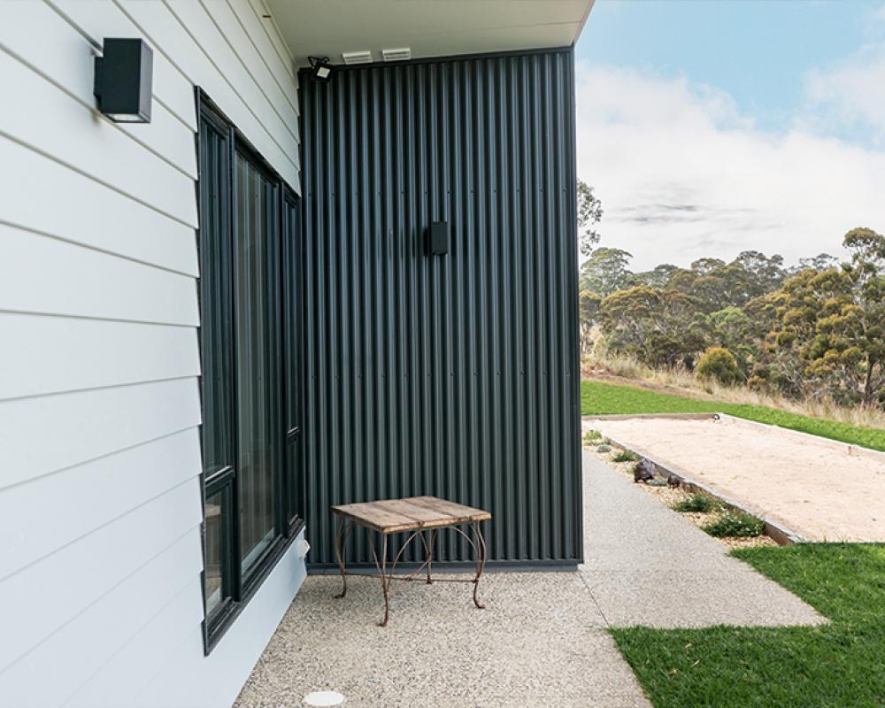 Contrasting house cladding with vertical COLORBOND® steel and white panel siding for a layered exterior look.