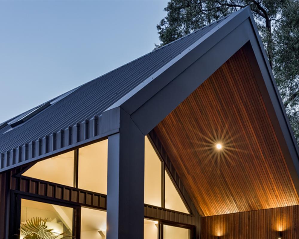 Dark pitched roof on modern home at dusk featuring clean roof profiles and COLORBOND® steel sheets