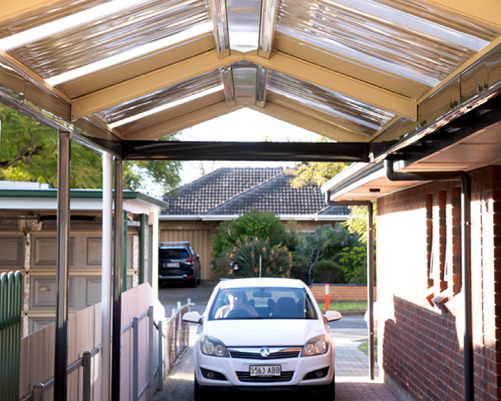 Drive-through carport attached to brick home, featuring steel roofing and beams in complementary COLORBOND® colours