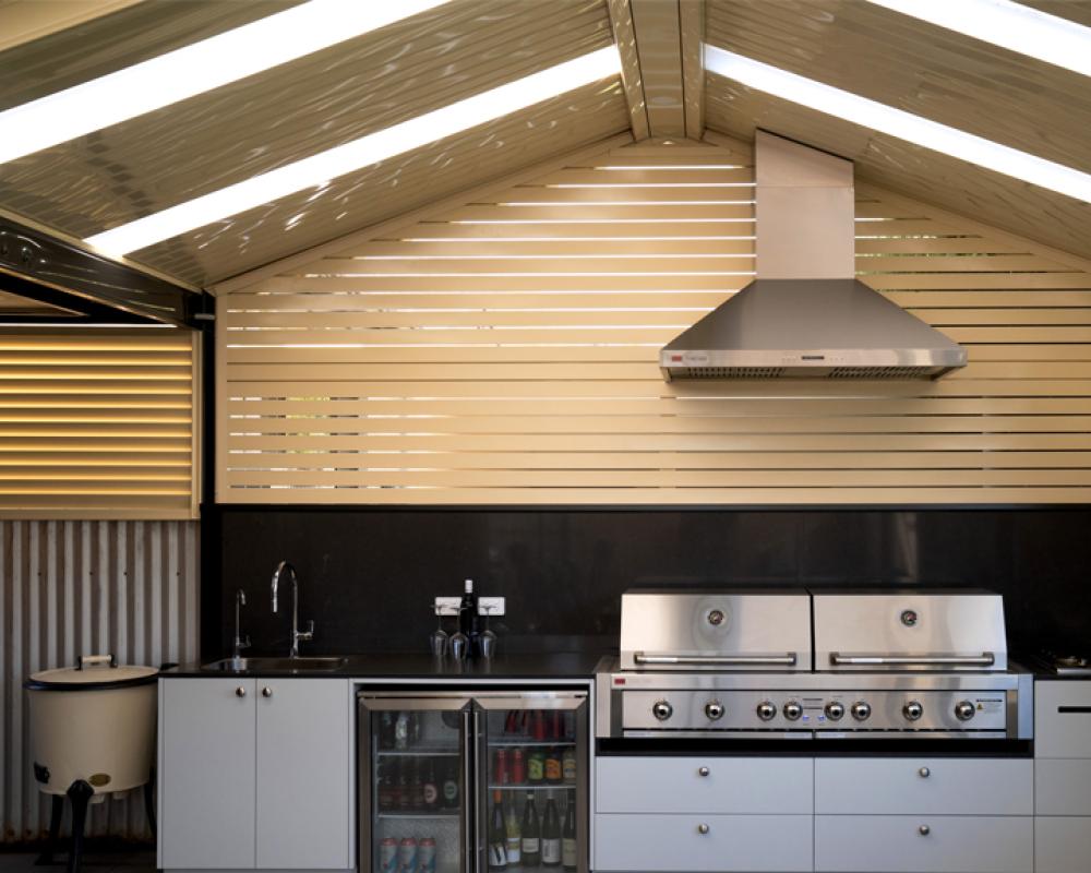 Outdoor kitchen under a patio roof designed for entertaining and year-round outdoor living