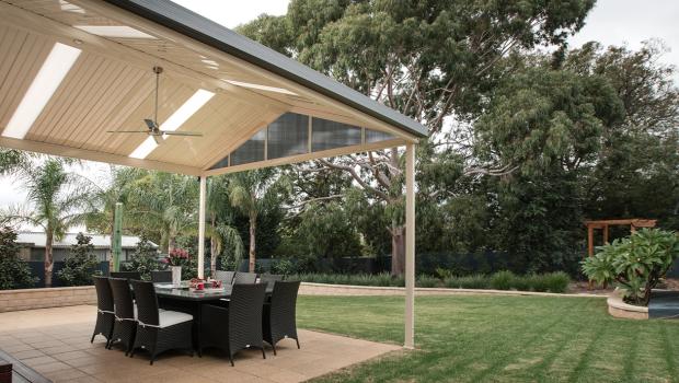 Gable patio with lined ceiling and fan, featuring outdoor dining and COLORBOND® steel roofing for backyard comfort.